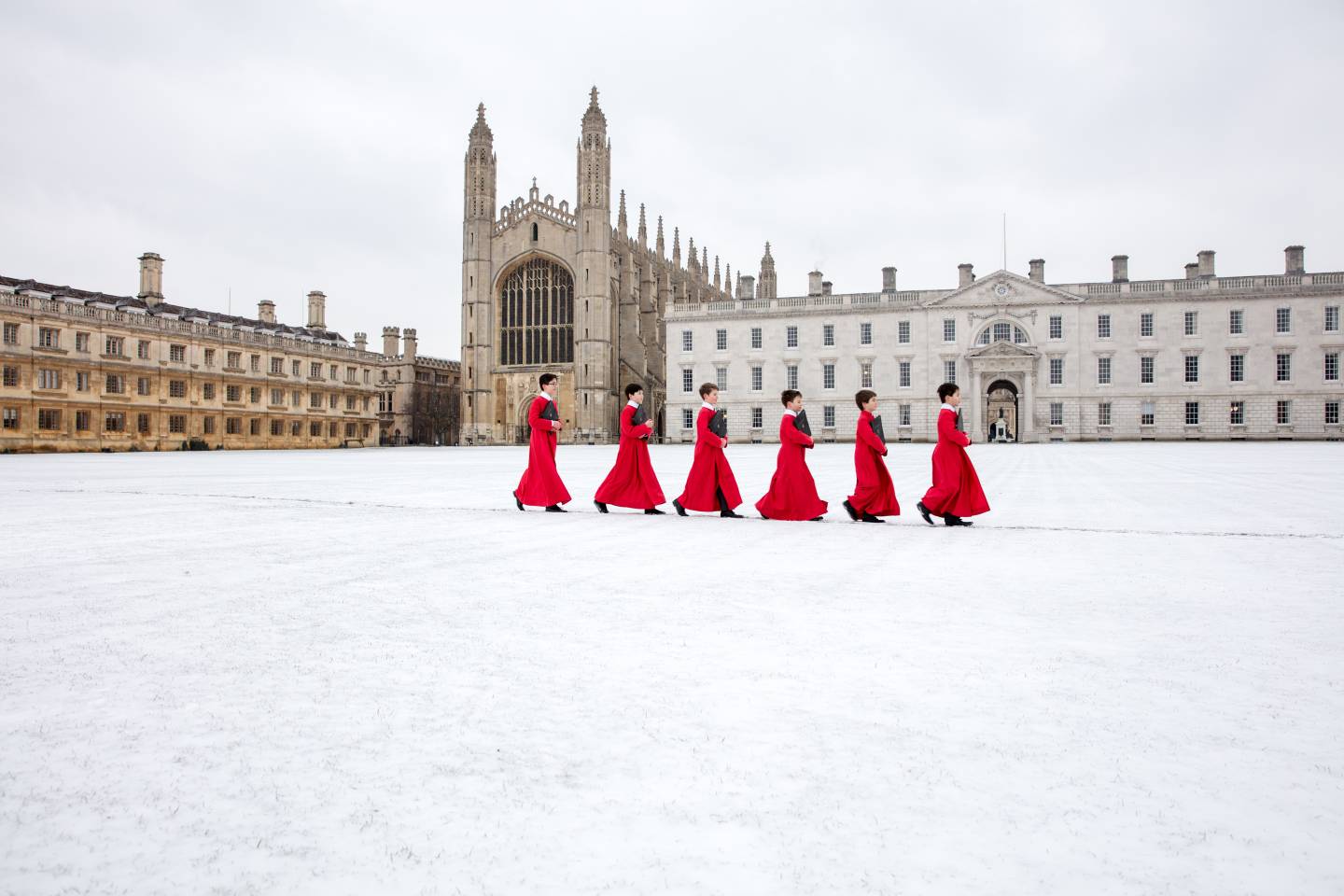 Choirboys walk in snow outside chapel